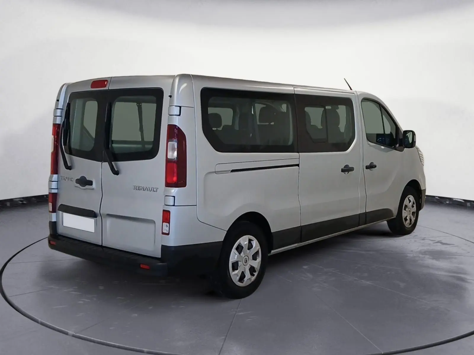 Vue 3/4 arrière droite d'un Renault Trafic Combi gris clair métal, avec vitres latérales et portes arrière vitrées.