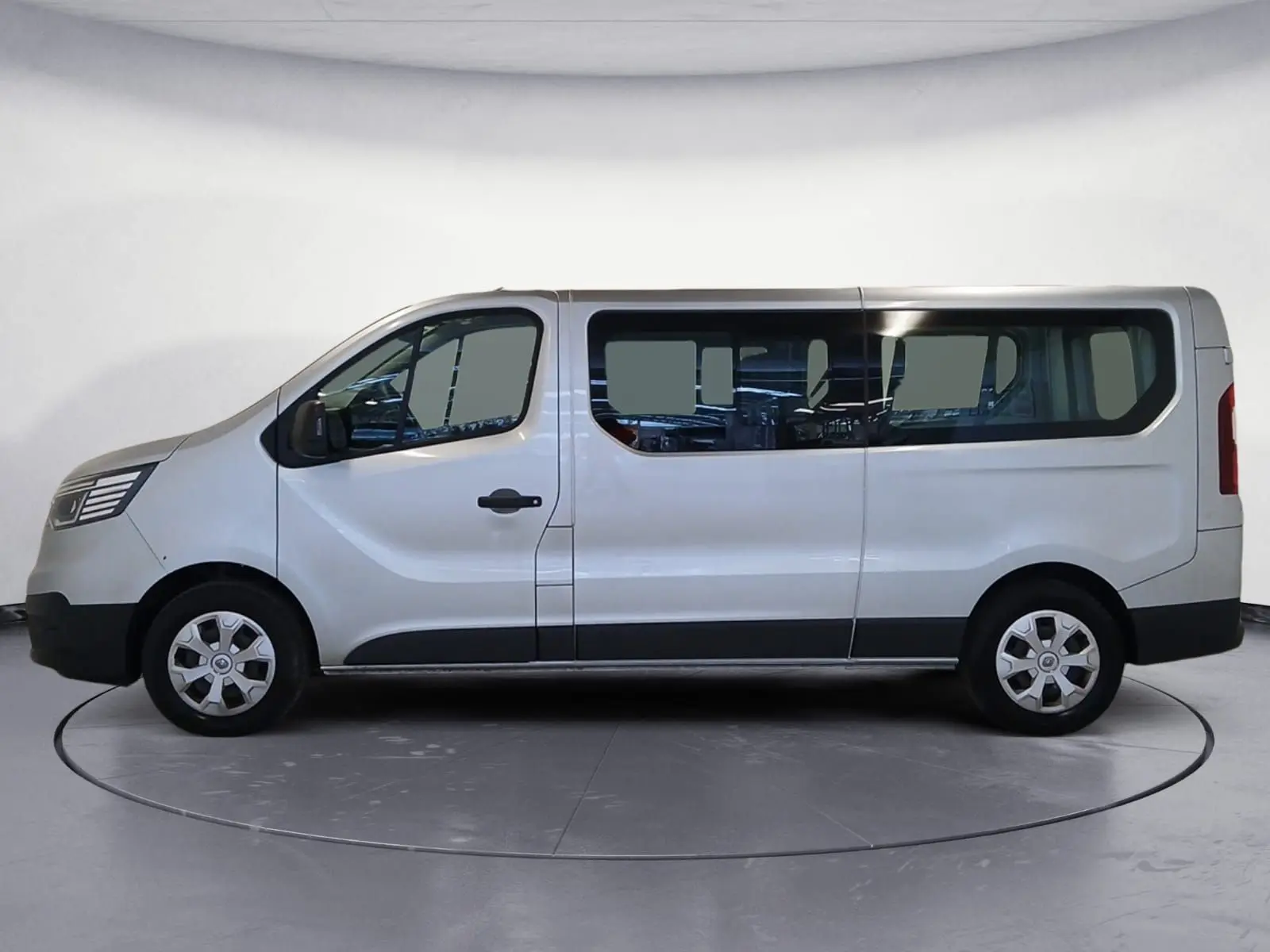 Profil droit d’un Renault Trafic Combi gris clair métal 2023, grand fourgon avec vitres latérales et jantes acier.