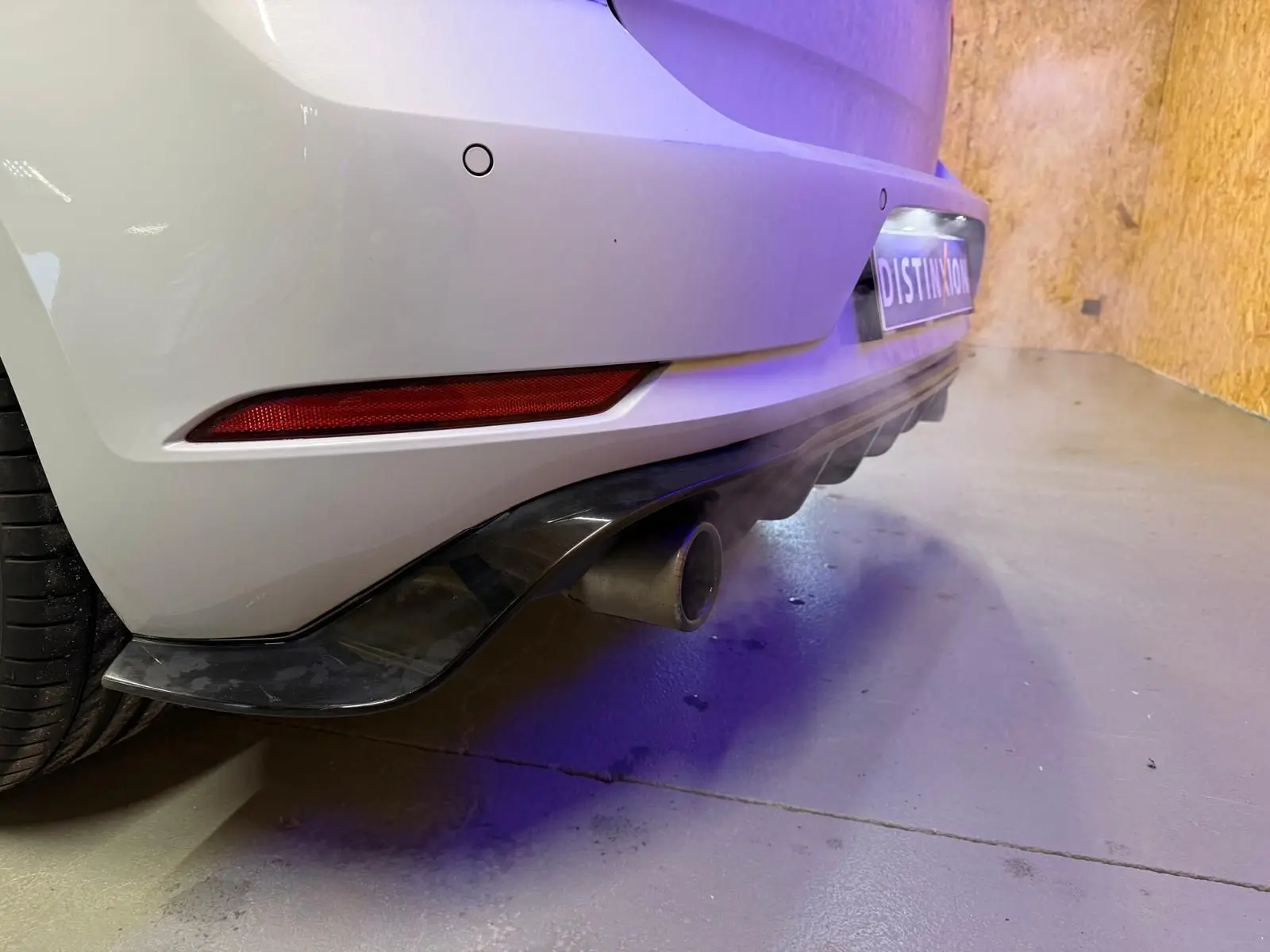 Vue 3/4 arrière droite d'une Volkswagen Golf GTI Performance gris clair avec jantes alu 19 pouces et sorties d'échappement chromées.