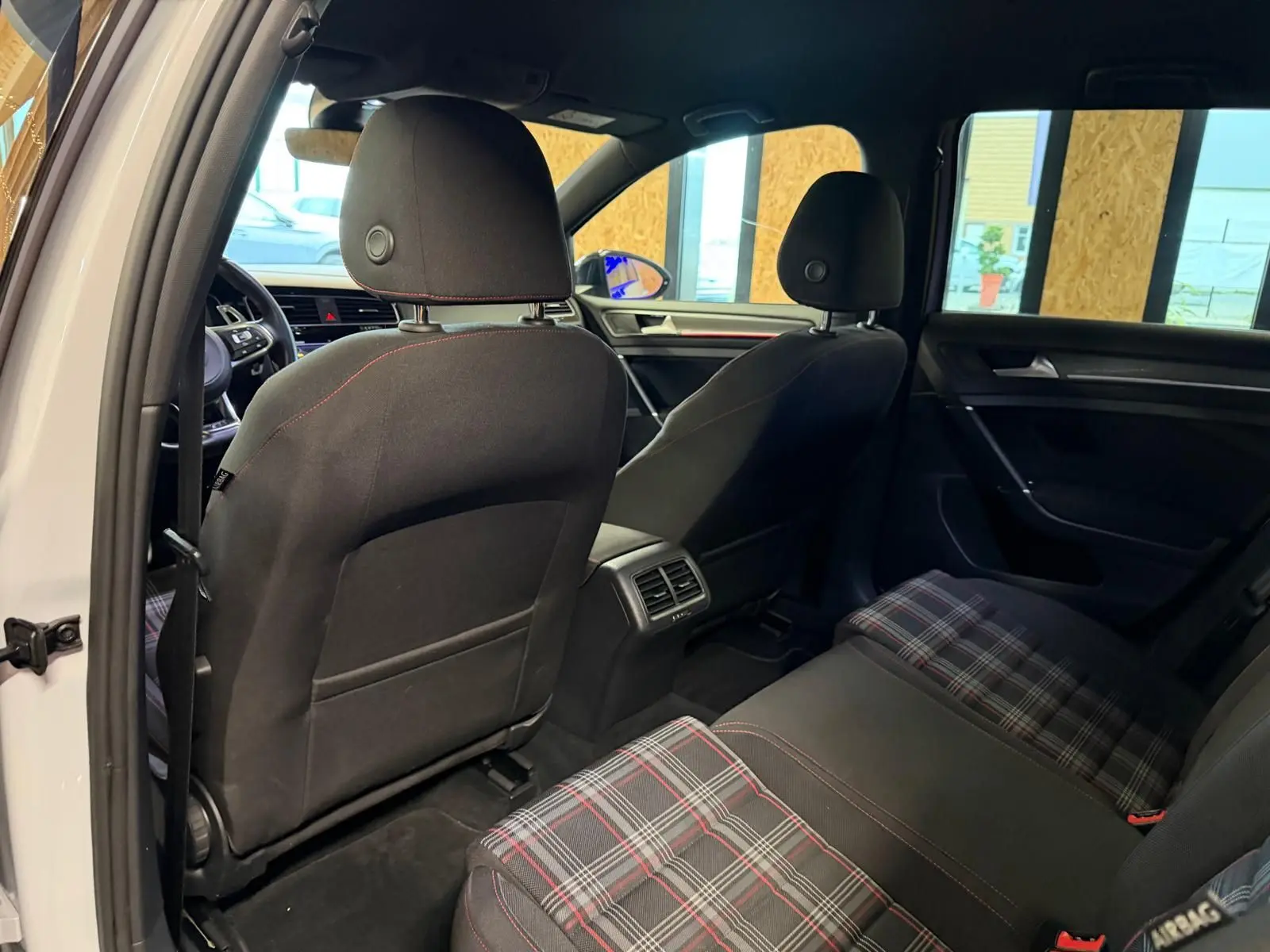 Vue rapprochée du volant sport noir avec surpiqûres rouges et tableau de bord numérique de la Volkswagen Golf GTI Performance.