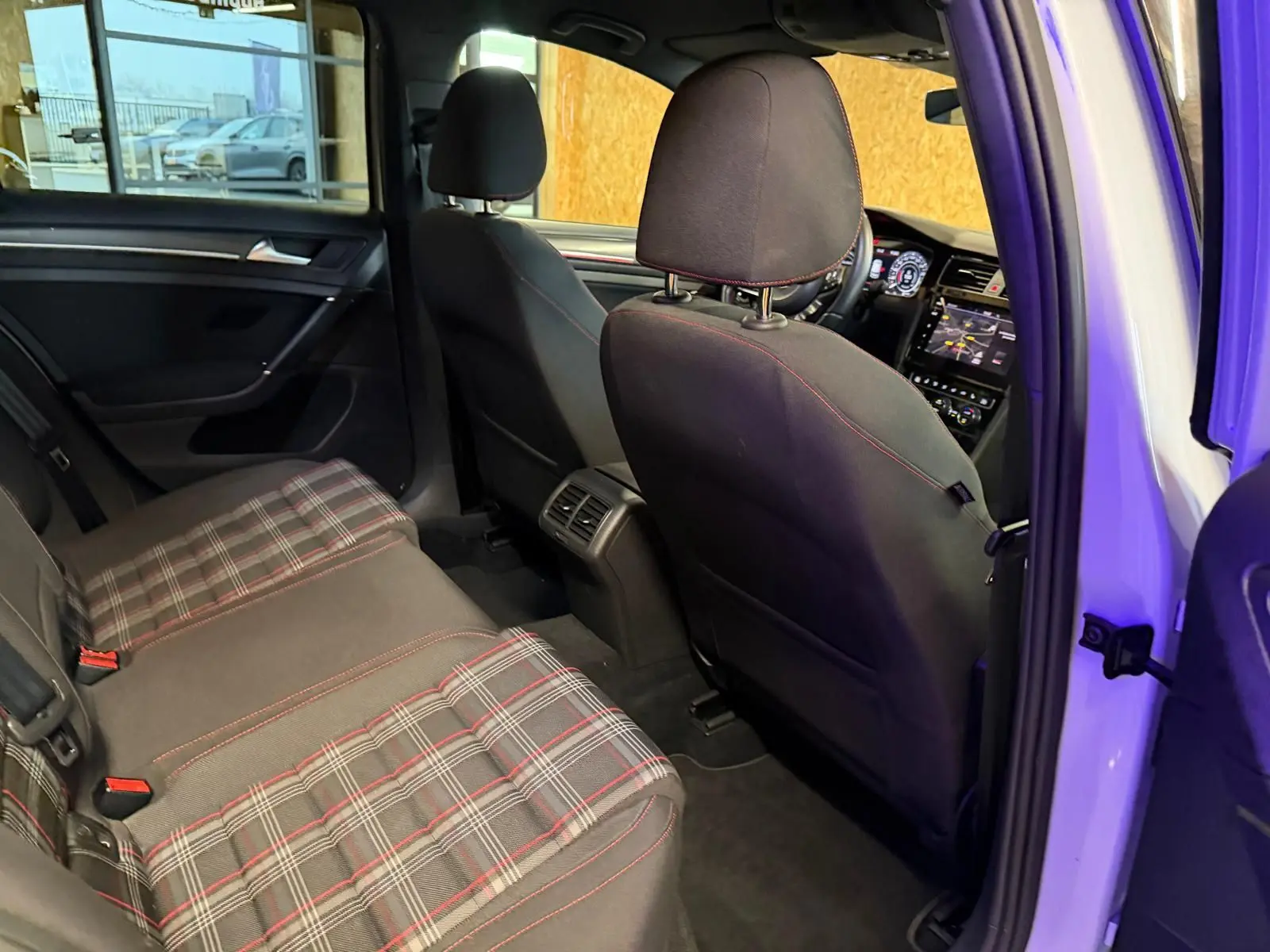 Vue intérieure sur la porte arrière droite ouverte d'une Volkswagen Golf GTI Performance grise, avec garniture noire et éclairage bleu subtil.