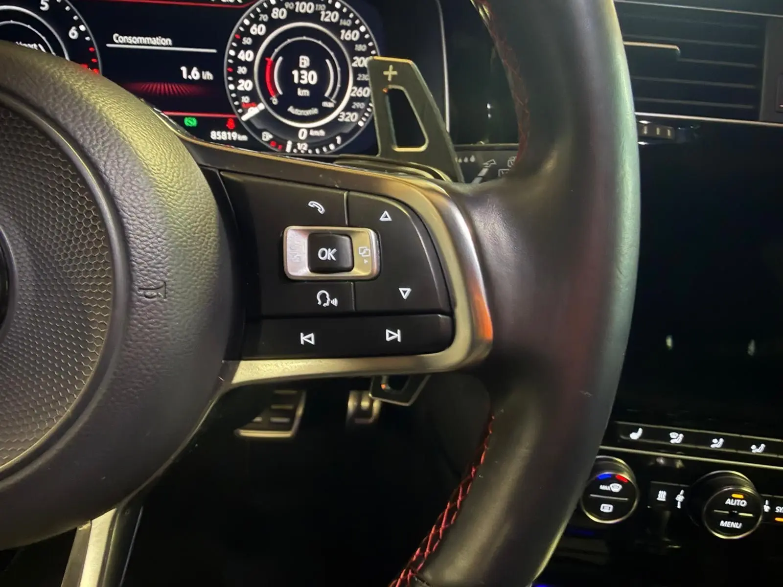 Vue intérieure de la porte avant gauche d'une Volkswagen Golf GTI Performance grise avec bandeau rouge et poignée argentée.