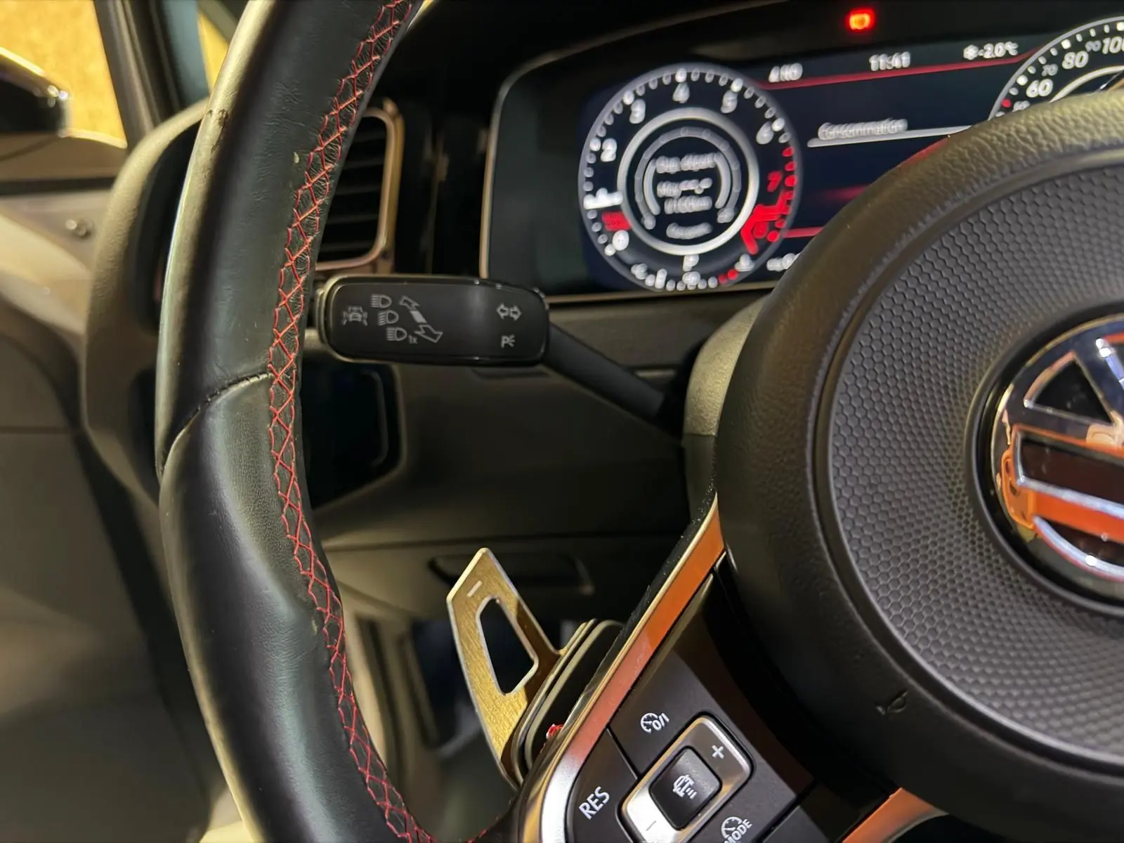 Vue intérieure côté conducteur d’une Volkswagen Golf GTI Performance 2018 avec sièges sport à motif tartan et coutures rouges.