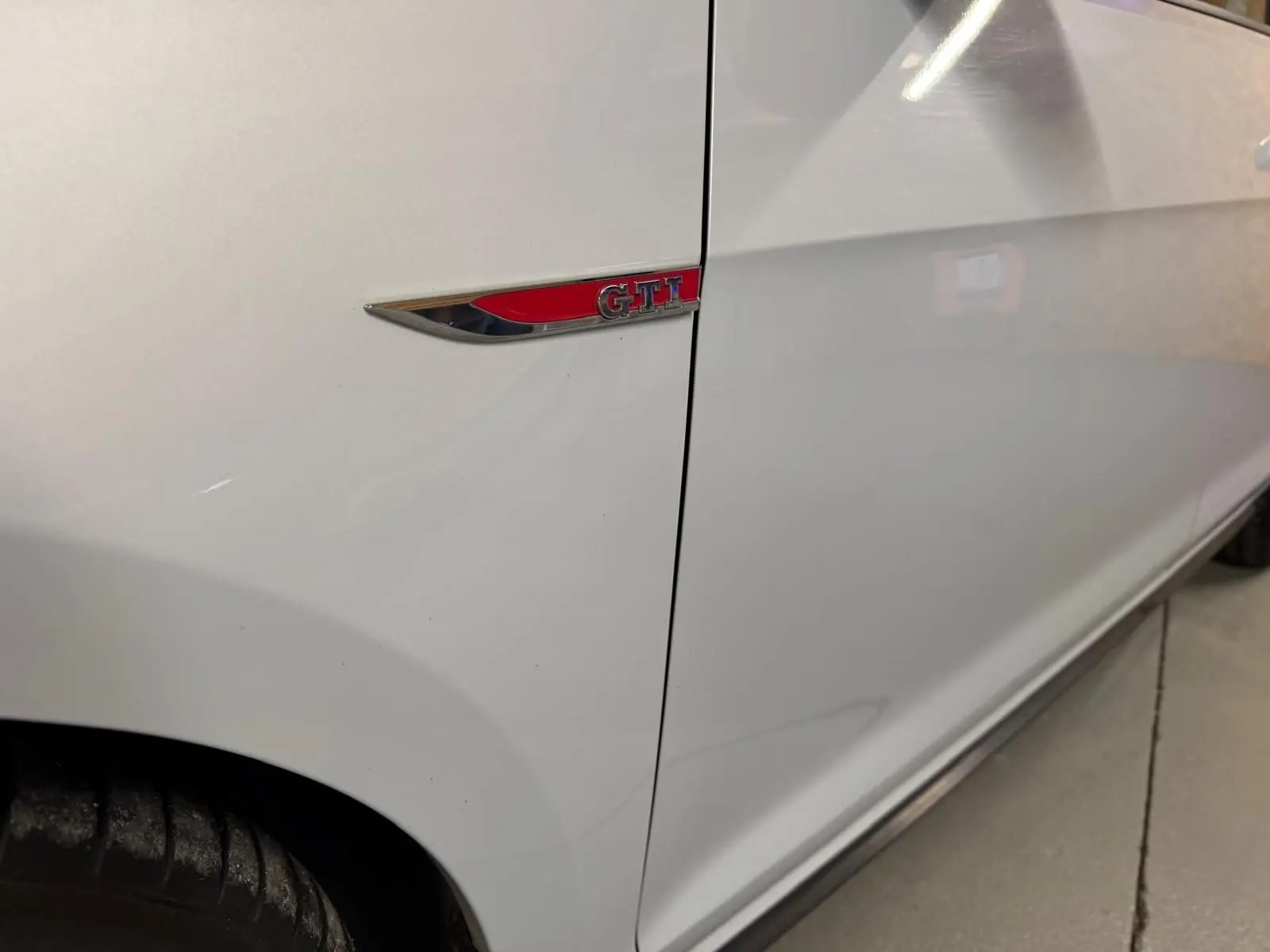 Gros plan sur la roue avant gauche gris clair d'une Volkswagen Golf GTI Performance avec étrier de frein rouge et jante alu 19 pouces.