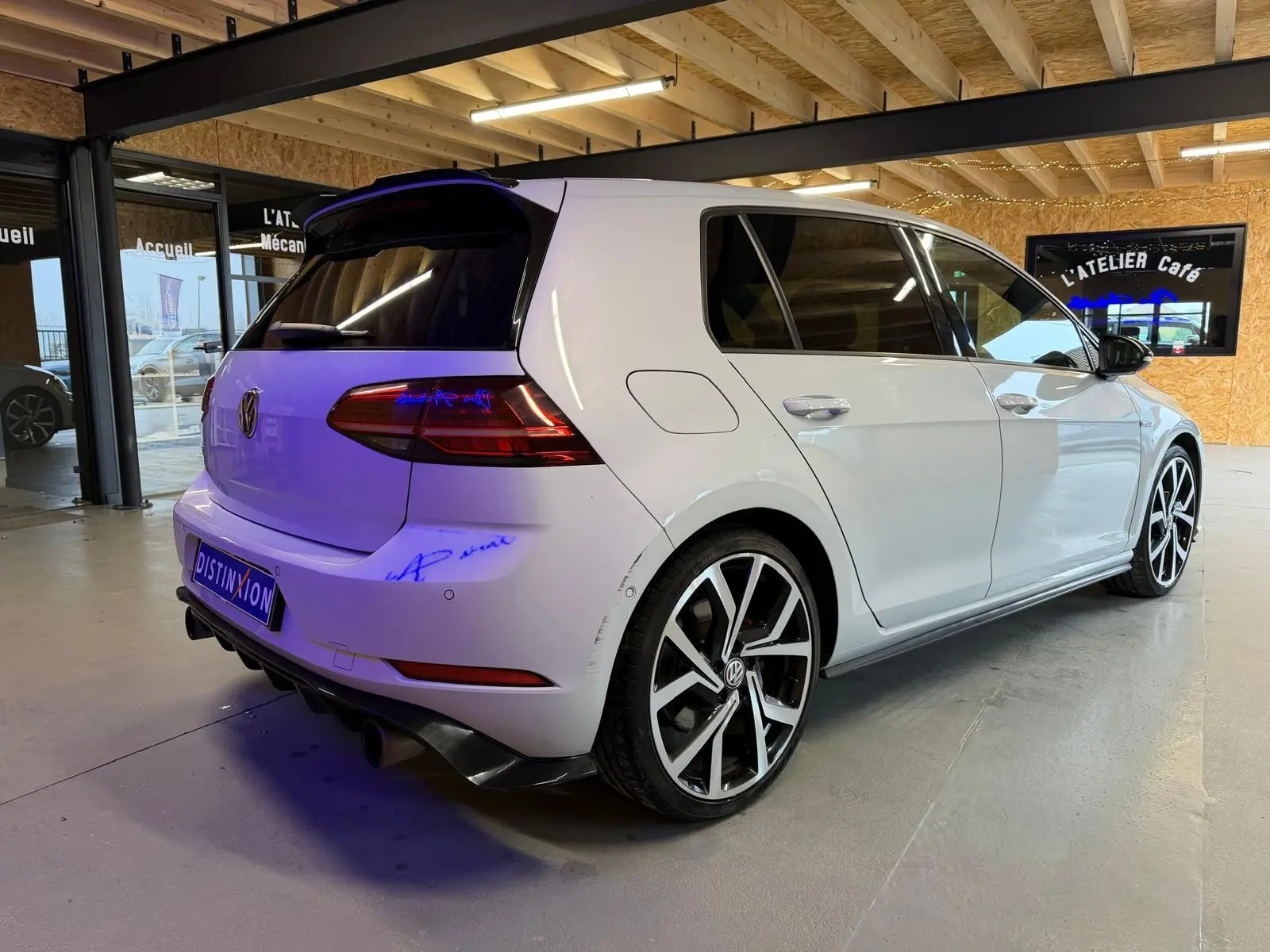 Vue avant d'une Volkswagen Golf GTI Performance gris clair avec calandre noire et détails rouges, en intérieur showroom.