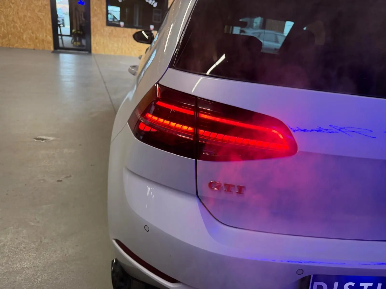 Vue arrière d'une Volkswagen Golf GTI Performance gris clair avec feux LED et double sortie d'échappement chromée.