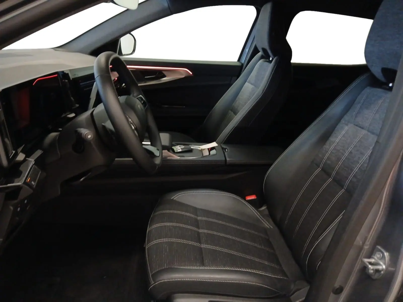 Intérieur Renault Austral E-Tech 2024 vu côté conducteur, sièges tissu gris et éclairage d'ambiance rouge sur porte.