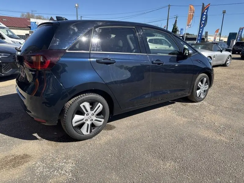 Honda Jazz 1.5 i-MMD bleu Nuit Radiant nacré vue de profil côté droit sur parking extérieur ensoleillé.