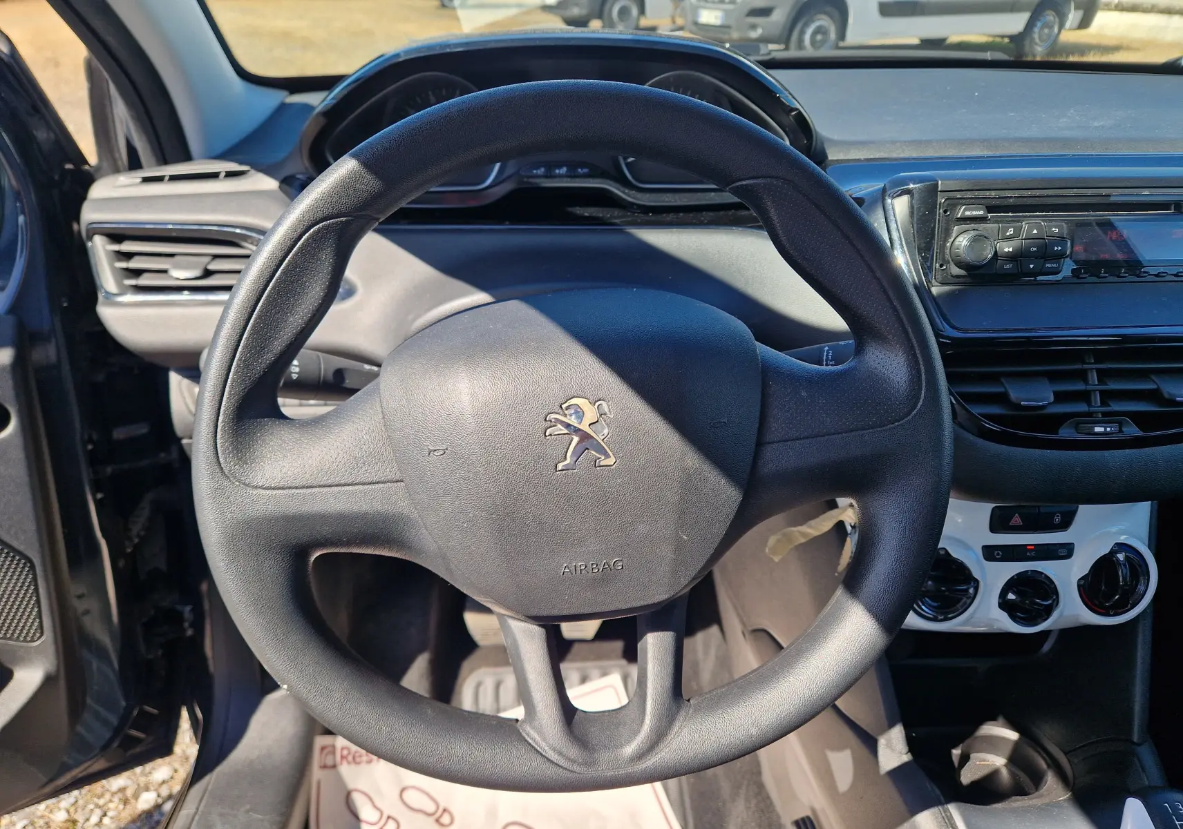 Vue intérieure centrée sur le volant Peugeot 208 2018, avec tableau de bord et commandes de climatisation visibles.