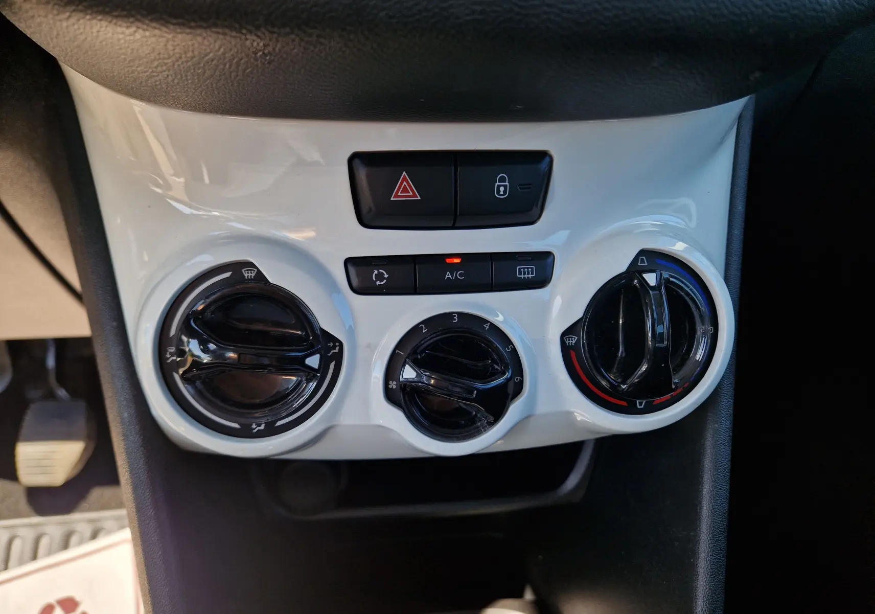 Vue rapprochée des commandes de climatisation blanches sur la console centrale d'une Peugeot 208 gris hurricane de 2018.
