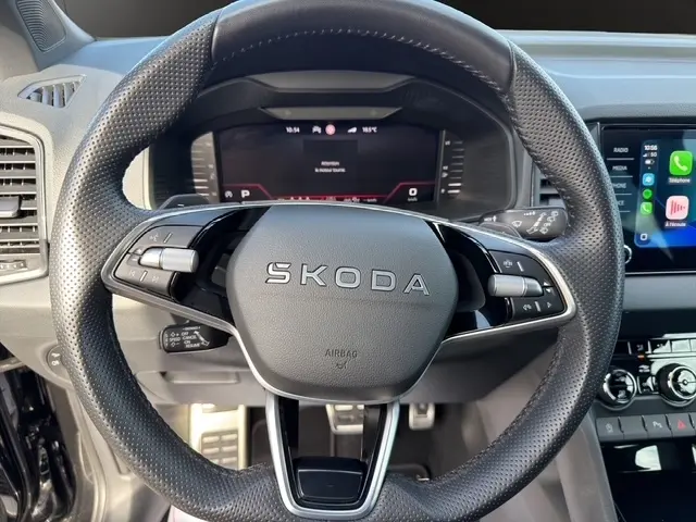 Vue rapprochée du volant en cuir perforé noir du Skoda Karoq 2025 avec tableau de bord numérique et écran tactile central.