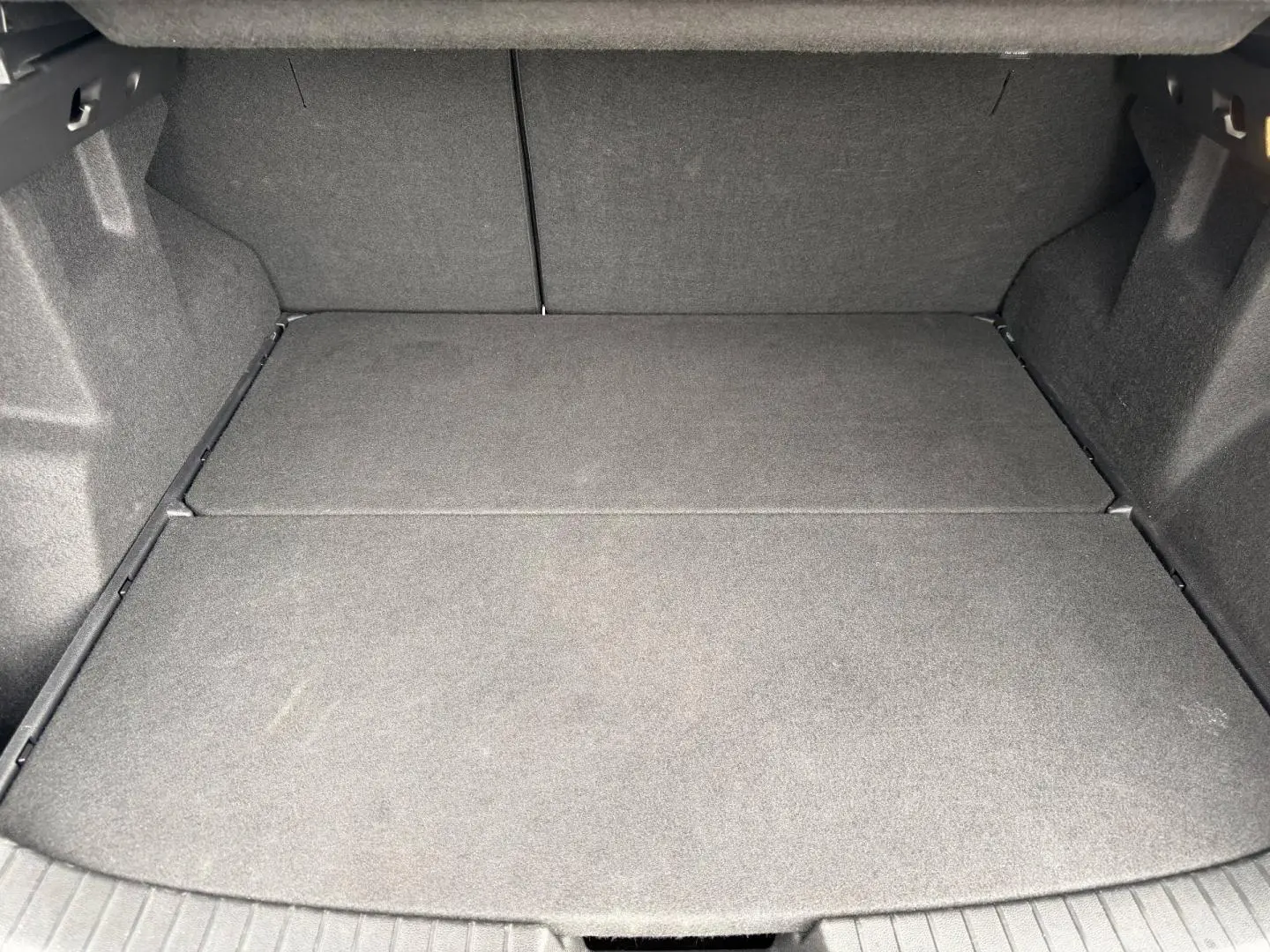 Coffre spacieux du Dacia Duster 2025, vue intérieure arrière, revêtement tissu gris foncé uniforme.