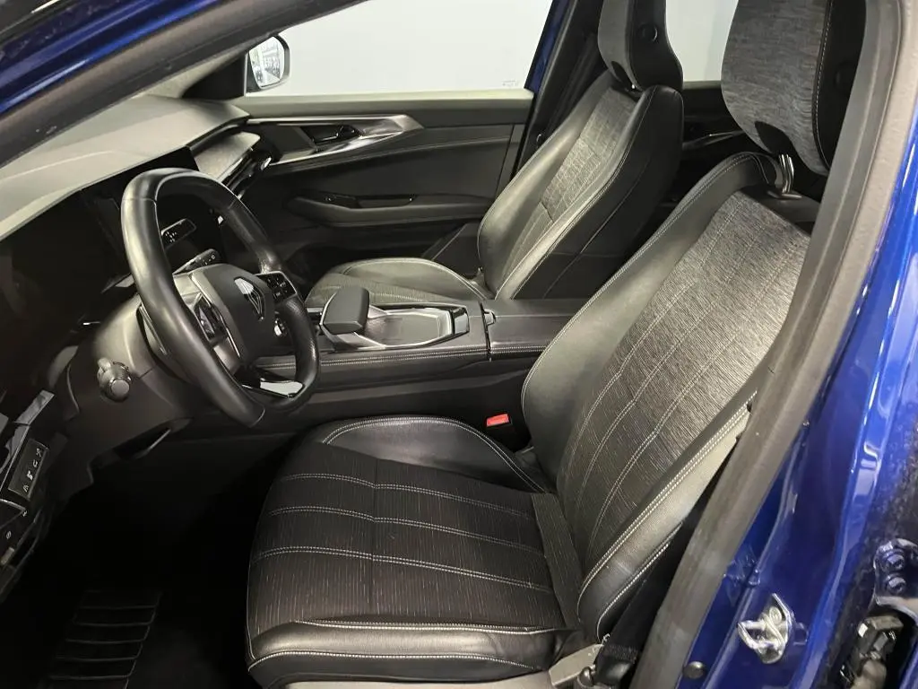 Vue intérieure côté conducteur du Renault Austral bleu, sièges en simili-cuir et tissu gris avec surpiqûres argentées.