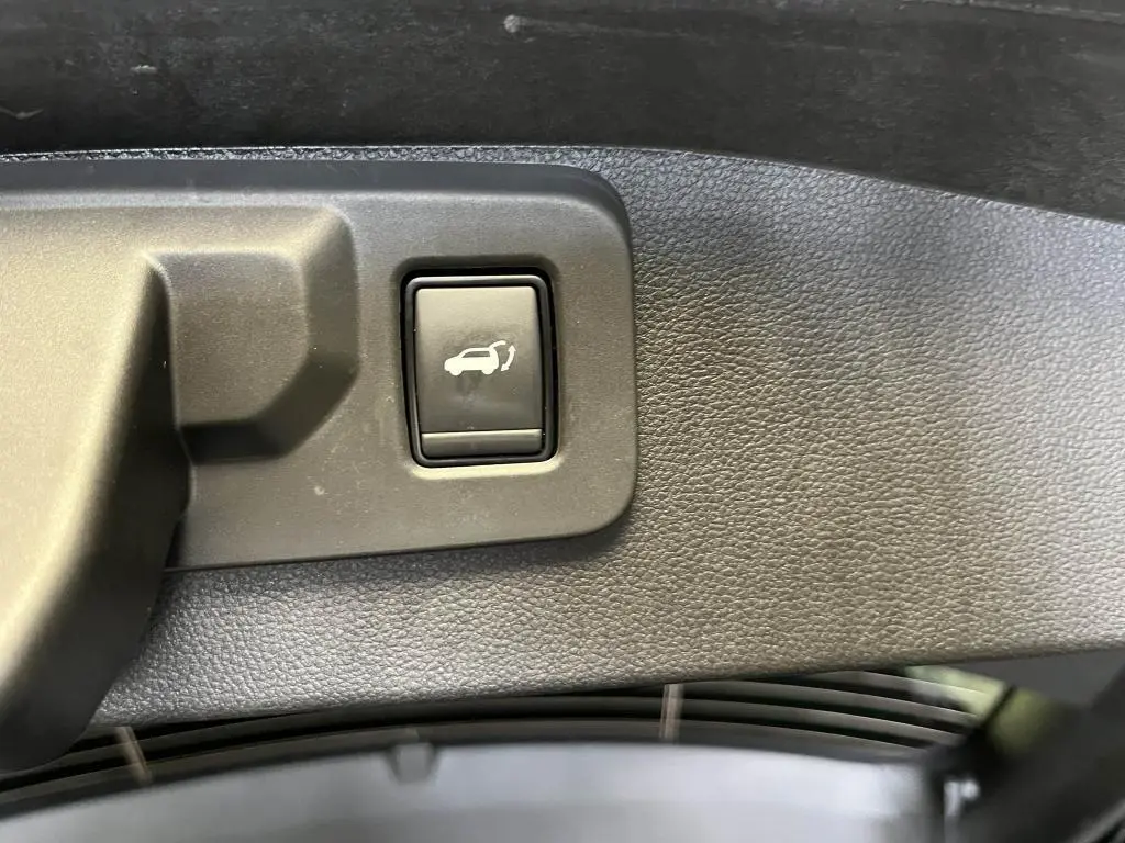 Bouton d'ouverture mains-libres du hayon sur le panneau intérieur noir du coffre du Renault Austral bleu 2023