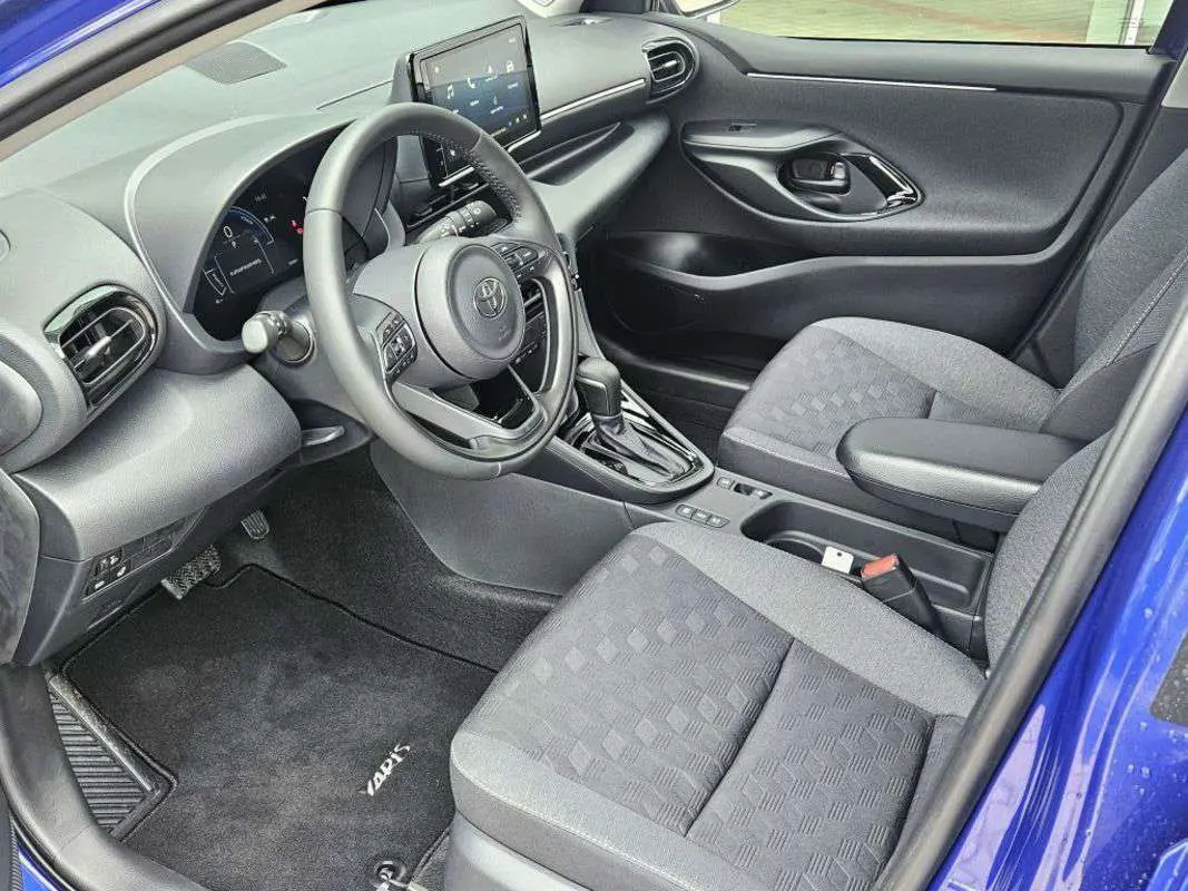 Intérieur avant droit de la Toyota Yaris 1.5 Hybrid 116 BVA Design 2025 avec sellerie grise et tableau de bord moderne.