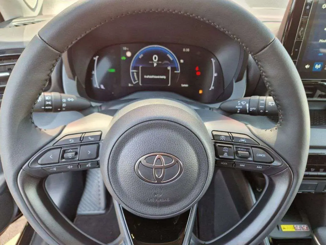 Vue rapprochée du volant multifonction de la Toyota Yaris 1.5 Hybrid 2025 avec tableau de bord numérique.