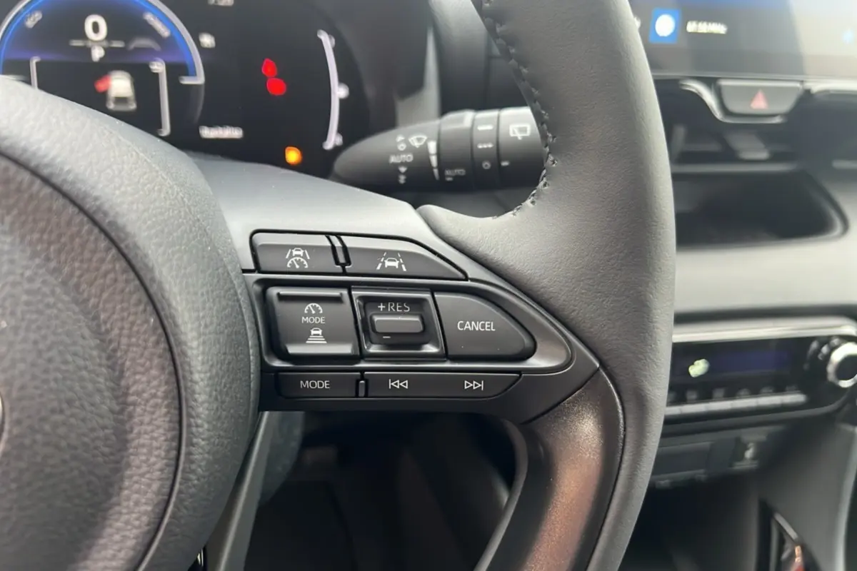 Vue rapprochée du volant de la Toyota Yaris 1.5 Hybrid 116 BVA Design 2025, montrant les commandes de régulateur de vitesse.