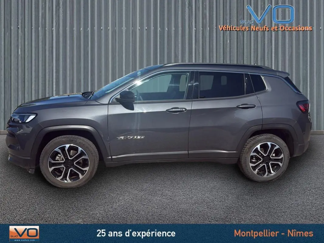 Profil côté gauche d'un Jeep Compass gris 2023 avec jantes 18 pouces, barres de toit et rétroviseurs noirs.