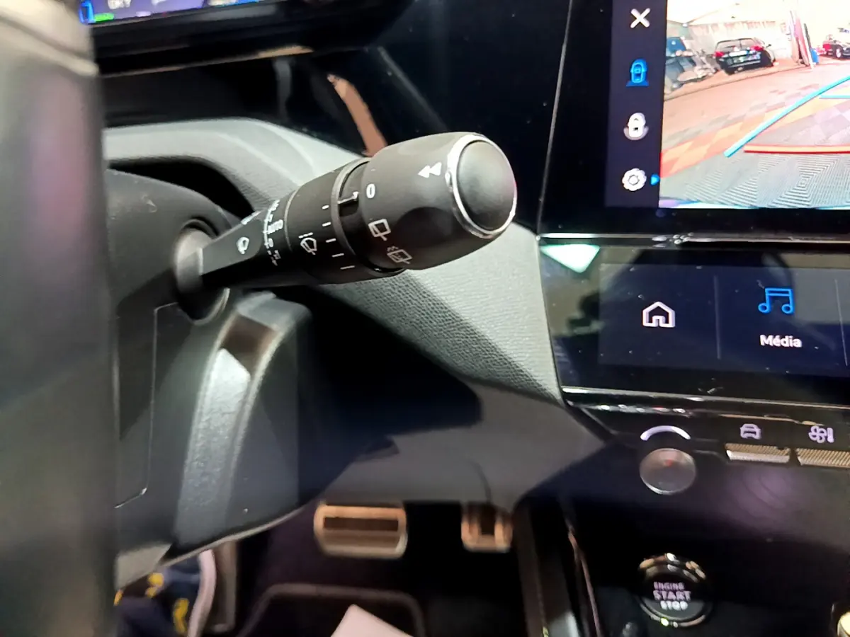 Gros plan sur la commande d’essuie-glace à gauche du volant dans l’habitacle noir de la Peugeot 308 PHEV GT 2022.