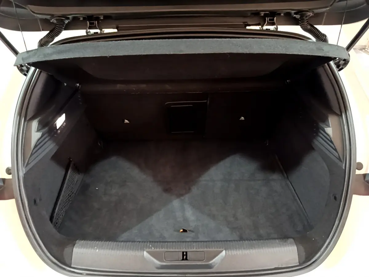 Coffre ouvert vu de l'arrière d'une Peugeot 308 PHEV 180 E-EAT8 GT blanche, intérieur noir et espace de rangement.
