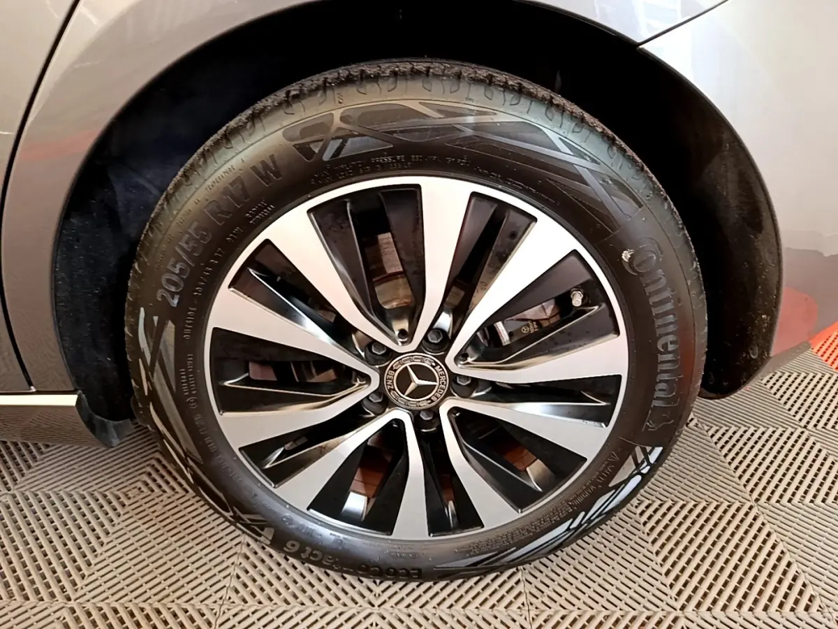 Gros plan sur la roue avant droite d'une Mercedes Classe A 250 e Business Line grise avec jante alliage noir et argent.