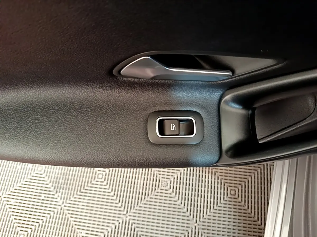 Détail de la poignée intérieure et bouton de verrouillage sur la porte côté gauche en cuir noir du Mercedes Classe A.