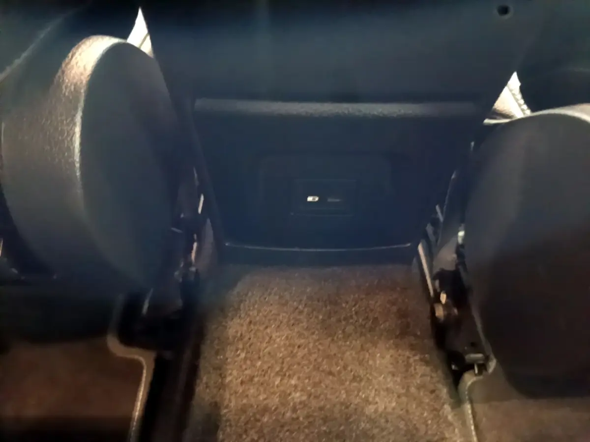 Vue intérieure arrière centrée sur la moquette et la partie inférieure des sièges avant noirs d'une Mercedes Classe A hybride.