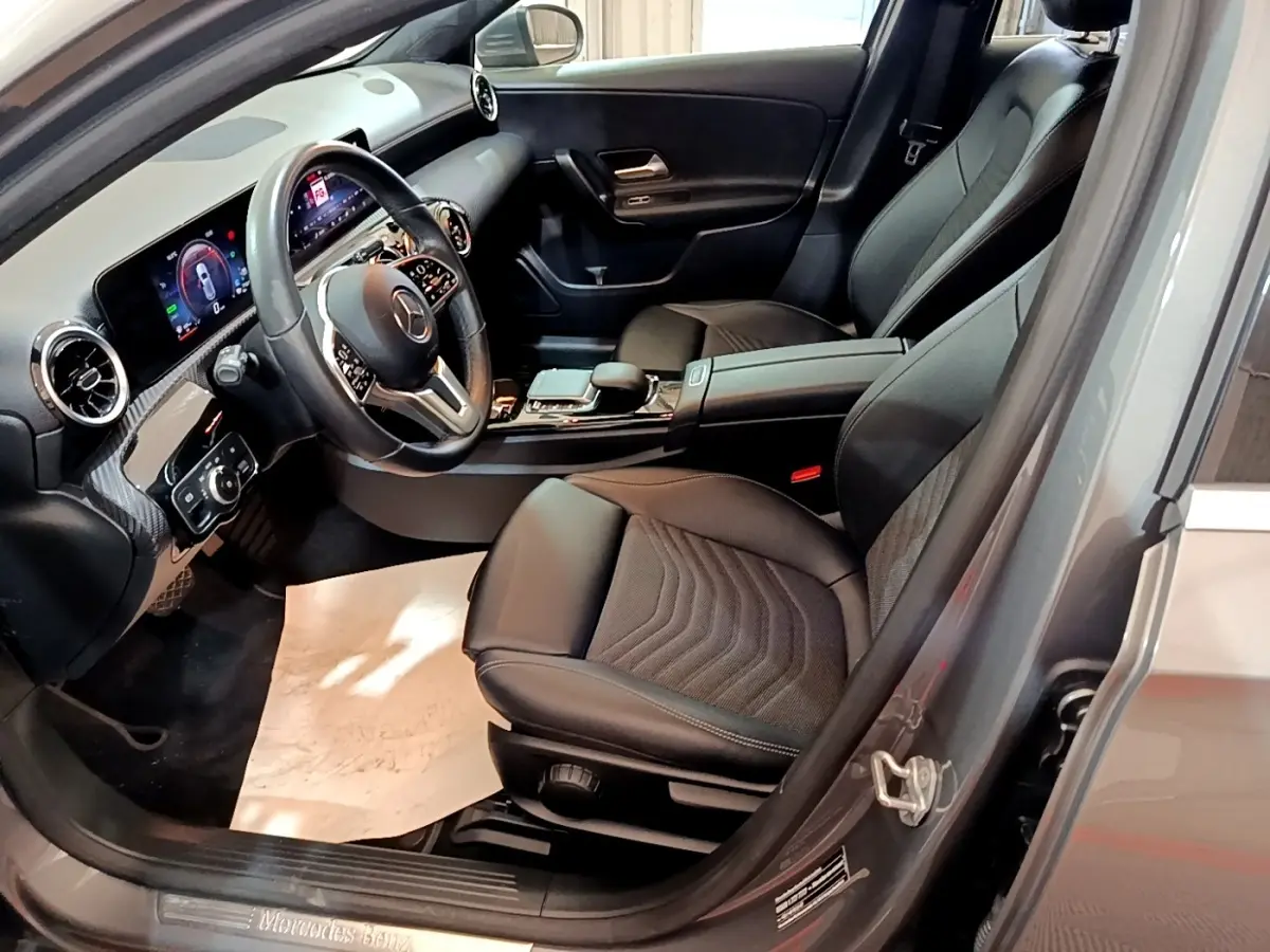 Vue intérieure côté conducteur de la Mercedes Classe A 250 e Business Line 2020 avec sièges cuir noirs et tableau de bord digital.