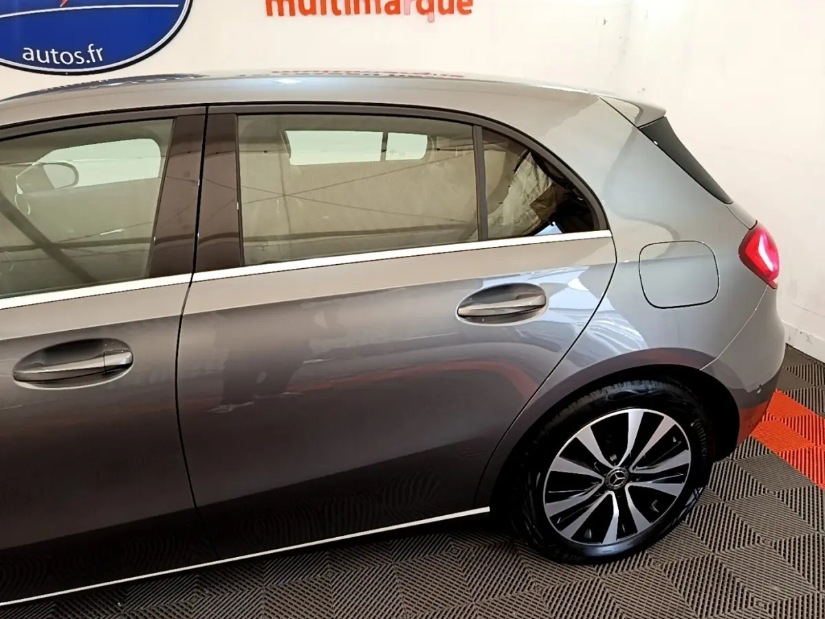 Vue latérale droite d'une Mercedes Classe A hybride rechargeable gris métallisé avec jantes distinctives et feux arrière allumés.