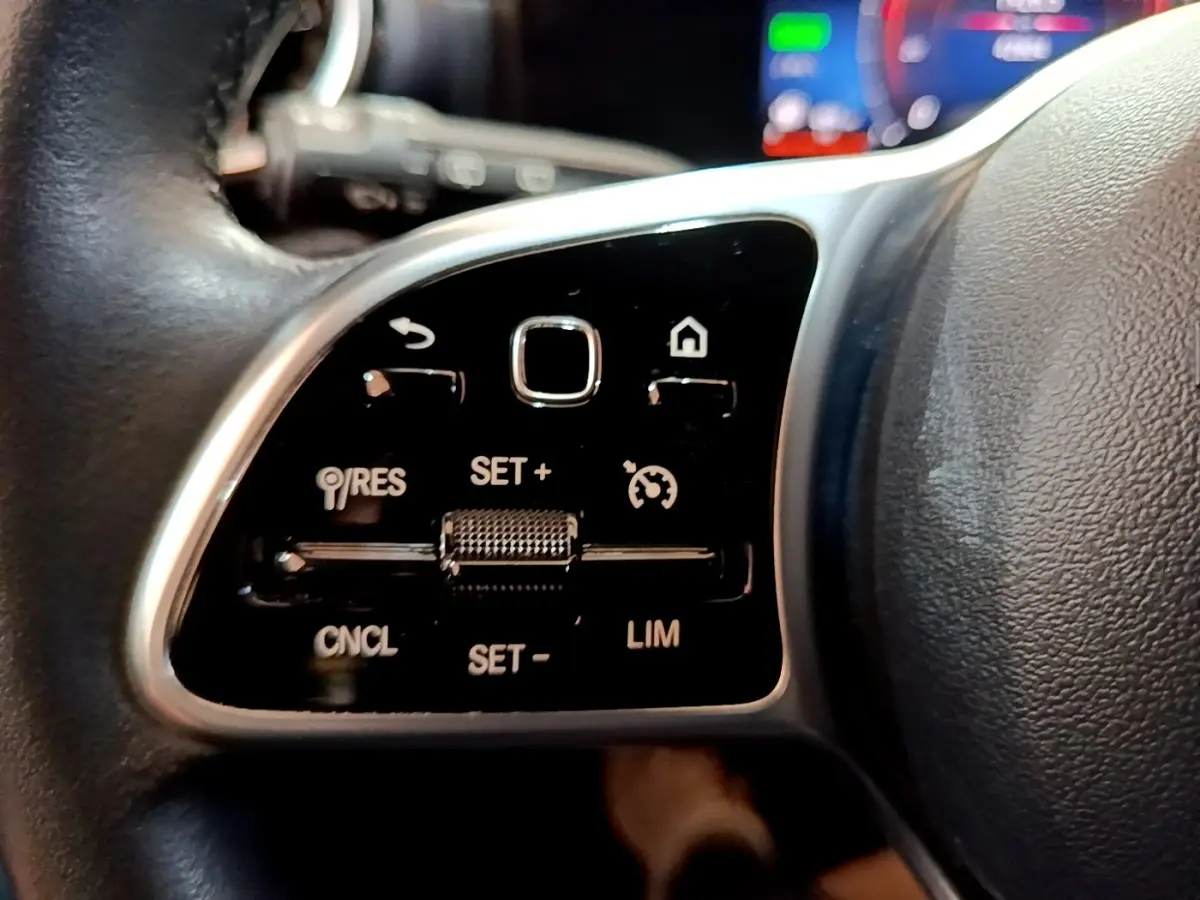 Gros plan sur les commandes multifonctions en cuir noir du volant de la Mercedes Classe A hybride rechargeable.