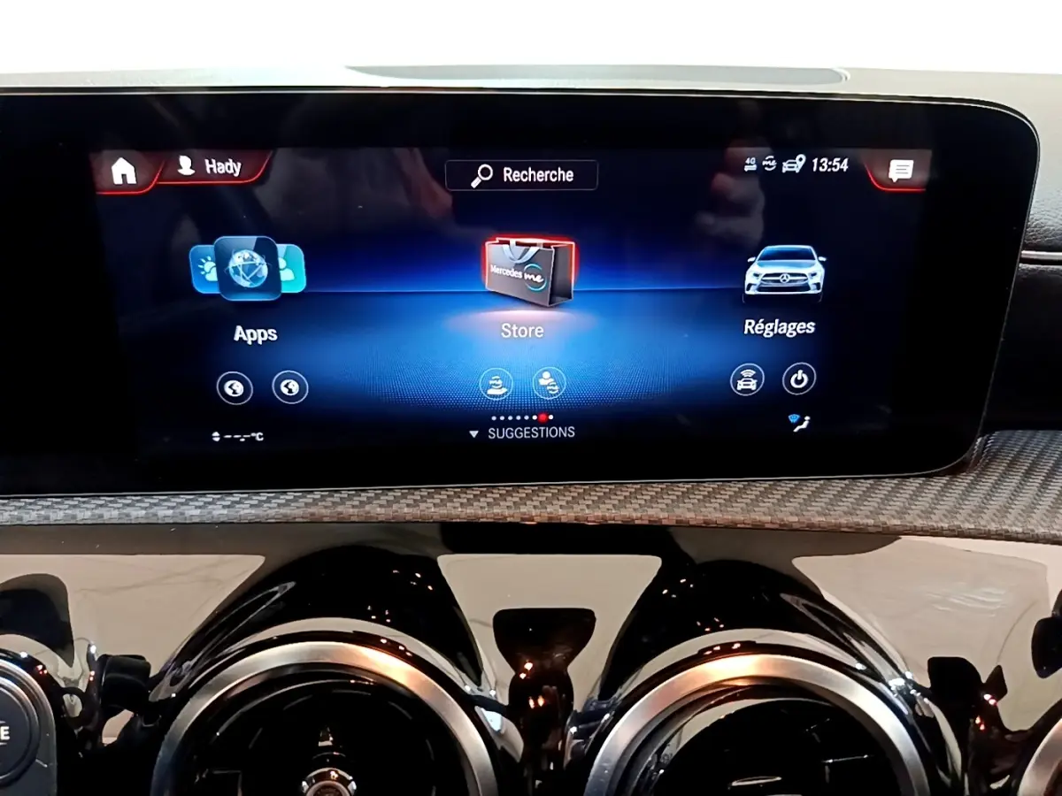 Gros plan sur l’écran tactile central et les aérateurs ronds noirs du tableau de bord de la Mercedes Classe A hybride.