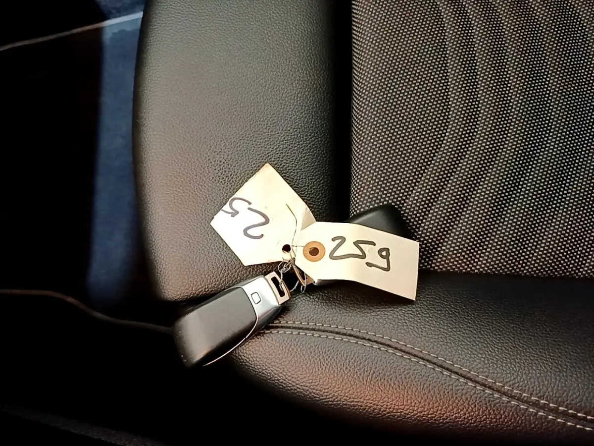 Gros plan sur la clé noire avec étiquette posée sur le siège avant en cuir noir de la Mercedes Classe A hybride rechargeable.