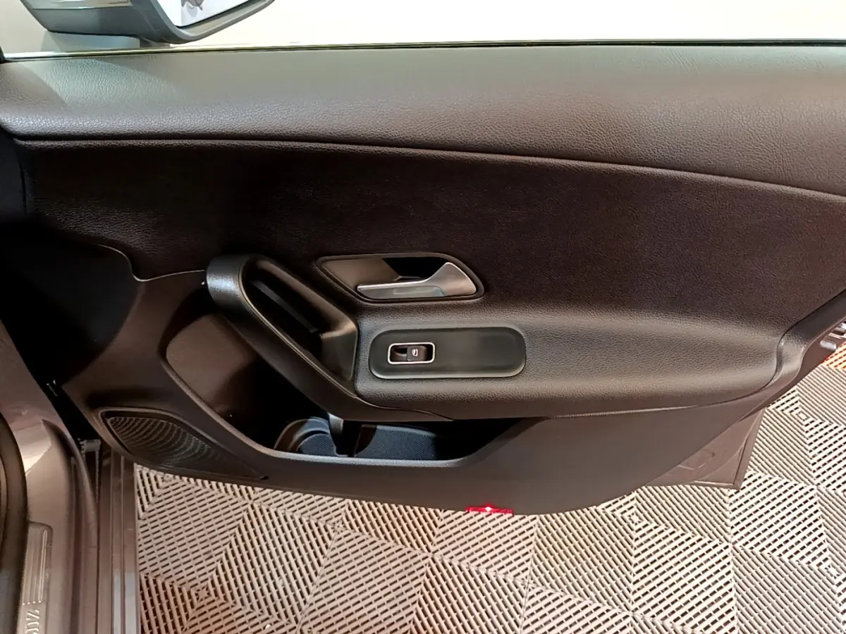 Vue intérieure du panneau de porte côté gauche noir de la Mercedes Classe A 250 e Business Line 2020 avec poignée et commande de vitre électrique.