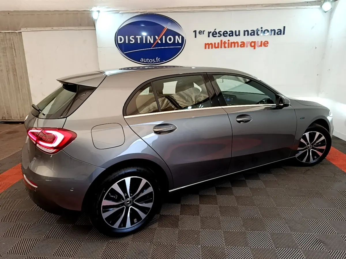 Vue 3/4 arrière droite d'une Mercedes Classe A A 250 e Business Line grise métallisée en intérieur showroom.