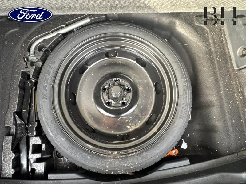 Gros plan sur la roue de secours noire et les outils de changement situés dans le coffre du SEAT Ateca blanc Nevada Métal.