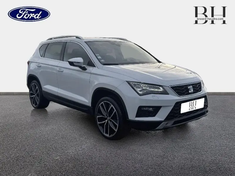 Vue 3/4 avant d’un SEAT Ateca blanc Nevada Métal avec jantes alliage noires et toit ouvrant panoramique visible.