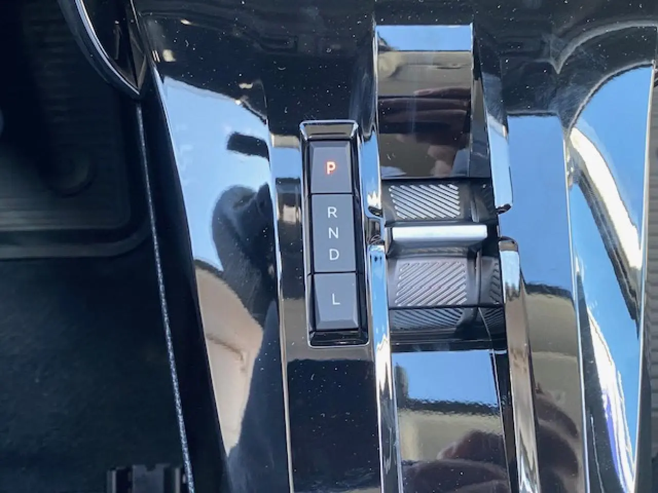 Gros plan sur la console centrale noire brillante du Citroën C3 Aircross 1.2i Hybride avec sélecteur de boîte automatique.
