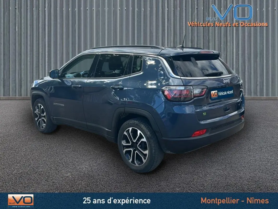 Vue 3/4 arrière gauche d'un Jeep Compass bleu 2023 avec barres de toit et jantes 18 pouces.