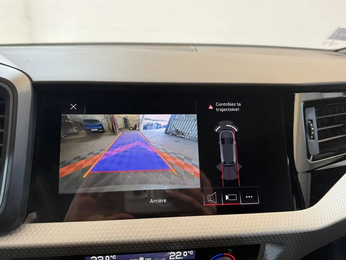 Écran central de l'Audi A1 2020 affichant la caméra de recul et l'alerte trajectoire en intérieur gris clair.