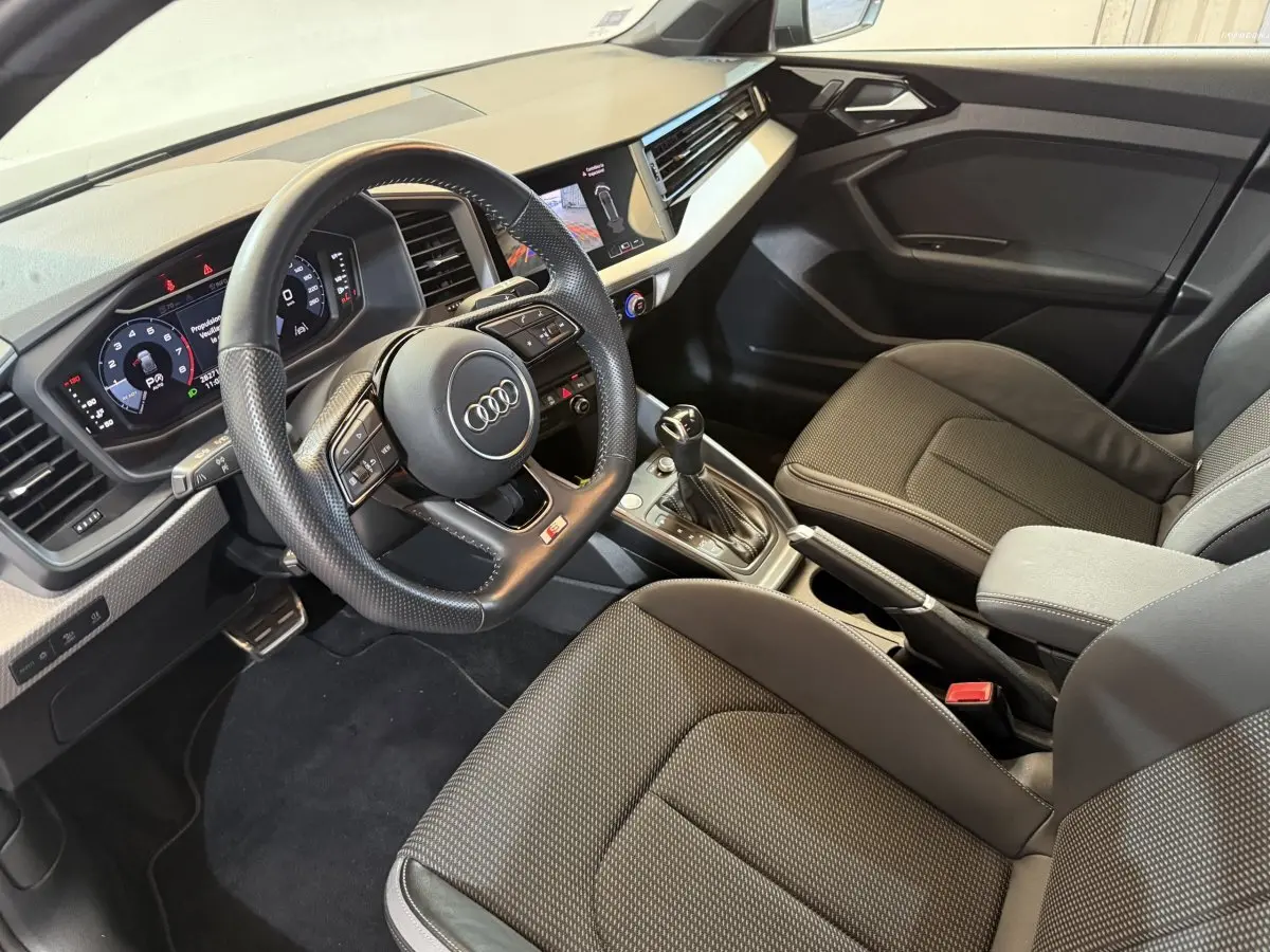 Intérieur Audi A1 2020 vu côté conducteur, volant cuir multifonctions et sièges tissu gris foncé.