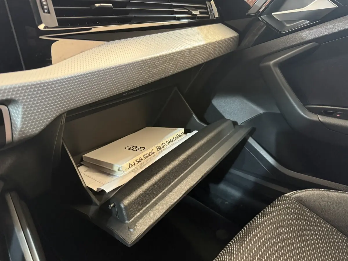Gros plan sur la boîte à gants ouverte côté passager de l'Audi A1 1.5 TFSI 2020 avec documents à l'intérieur.