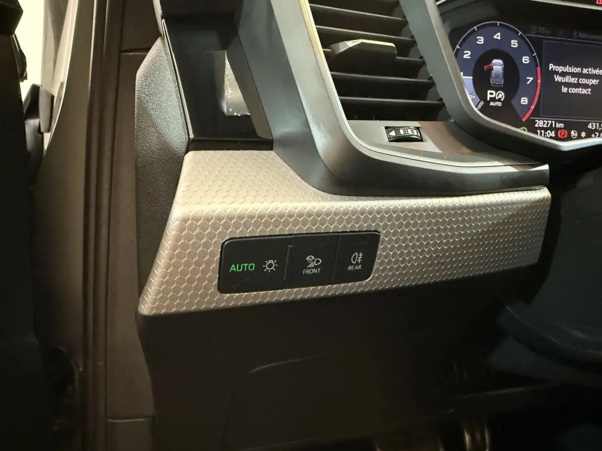 Détail du tableau de bord côté gauche de l'Audi A1 2020 avec commandes d'éclairage et finition gris texturé.