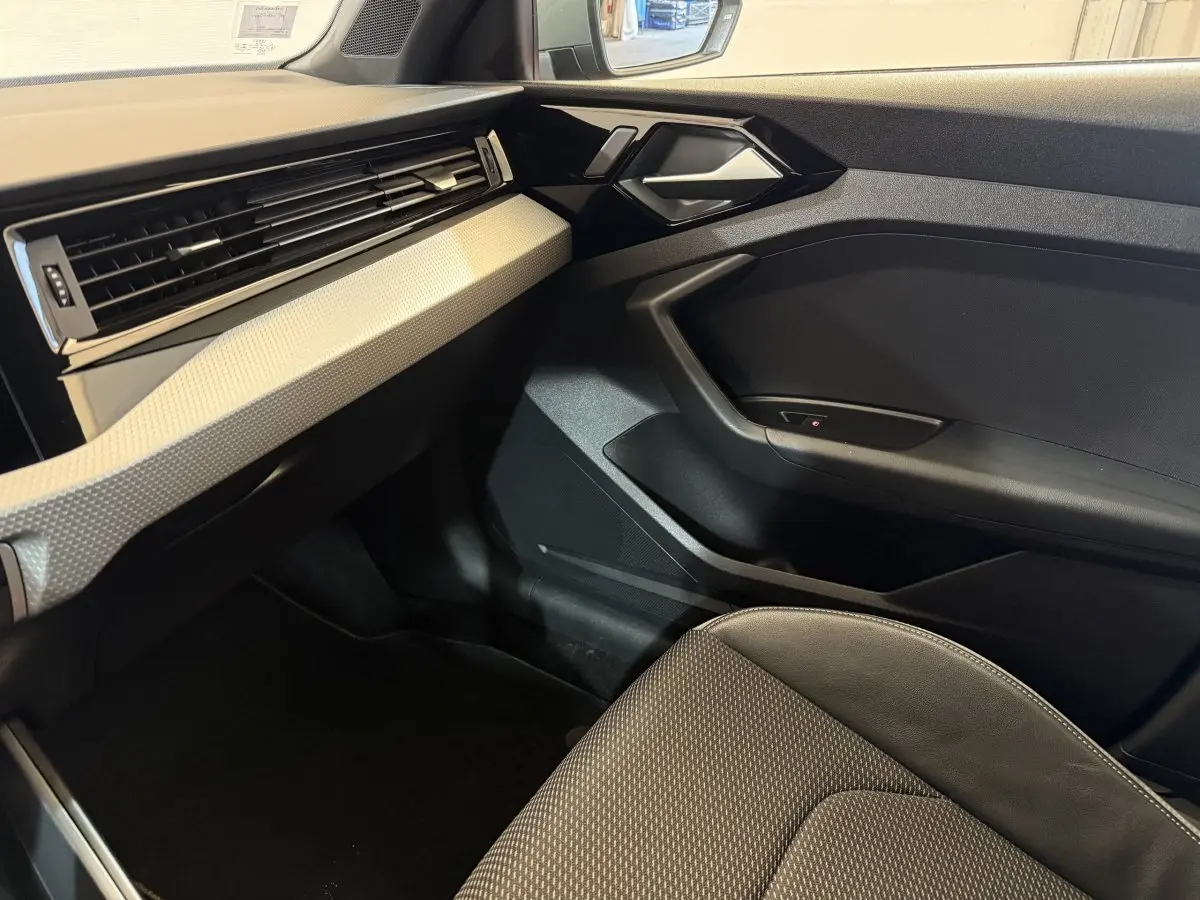 Intérieur côté passager de l'Audi A1 1.5 TFSI S line 2020 avec tableau de bord gris clair et siège tissu noir.