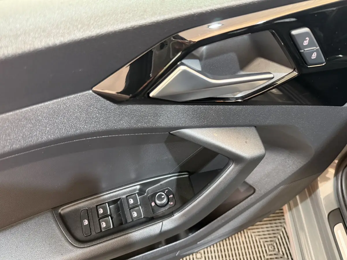 Détail de la porte côté conducteur d'une Audi A1 gris foncé avec commandes de vitres et rétroviseurs électriques.