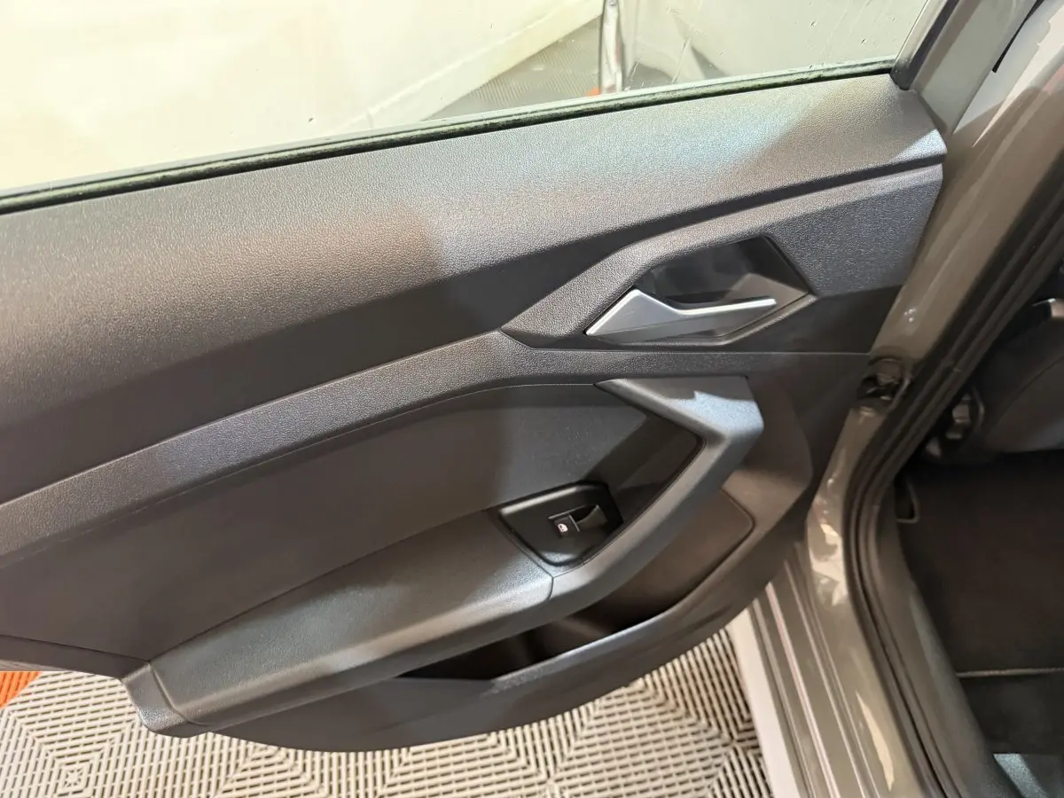 Gros plan sur la porte côté gauche gris foncé de l'Audi A1 1.5 TFSI S line avec poignée intérieure argentée.