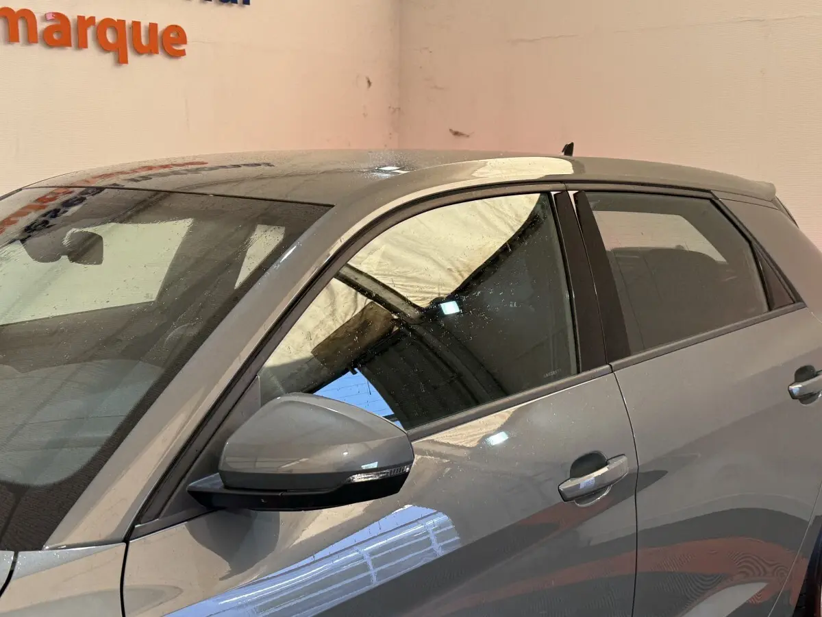 Vue latérale côté gauche d'une Audi A1 gris foncé 2020 avec rétroviseur et poignées assortis.