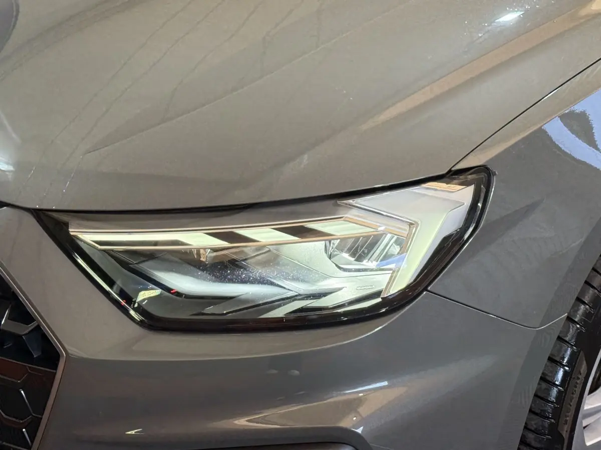 Gros plan sur le phare avant droit d'une Audi A1 gris foncé 2020, mettant en valeur son design LED moderne.