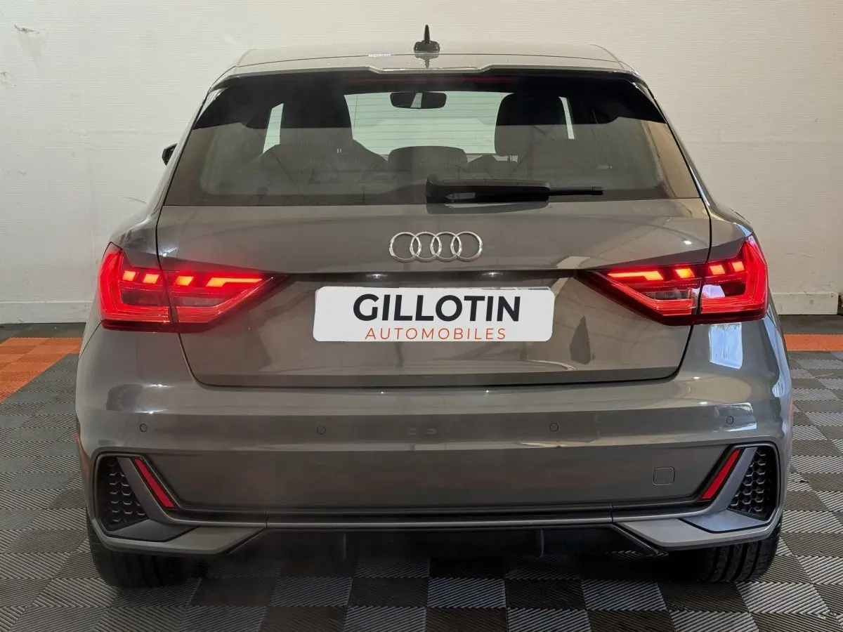 Vue arrière d'une Audi A1 1.5 TFSI S line gris foncé avec feux LED allumés et pare-chocs sport.