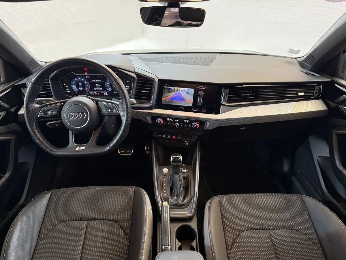 Vue intérieure avant de l'Audi A1 S line 2020, tableau de bord moderne avec écran digital et volant cuir multifonctions.