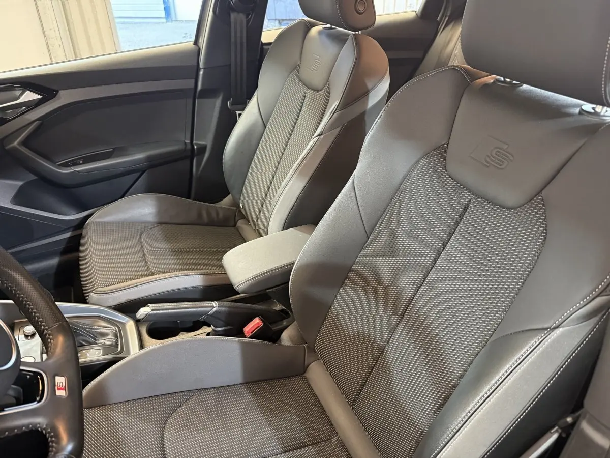 Vue intérieure côté conducteur de l'Audi A1 S line 2020, sièges sport gris avec logo S embossé sur appuie-tête.